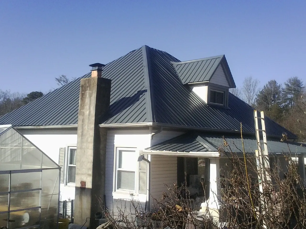 Dark blue standing seam metal roof on a white farmhouse with dormer — Slate & Tile Roof Repair by Roofing Brothers in Arley