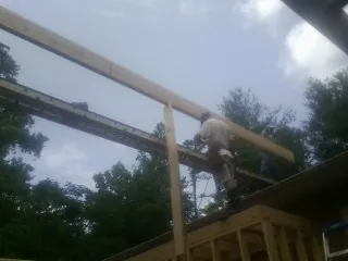Carpenter setting a ridge beam over a new addition frame — Ice Dam Removal by Roofing Brothers in Arley
