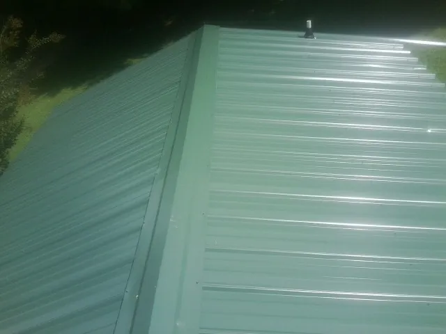 New green metal panels meeting at the ridge of a roof — Flat Roof Repair work by our crew in Arley