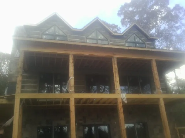 Dormers and porch framing on a large log home under construction — Roof Coating work by our crew in Arley