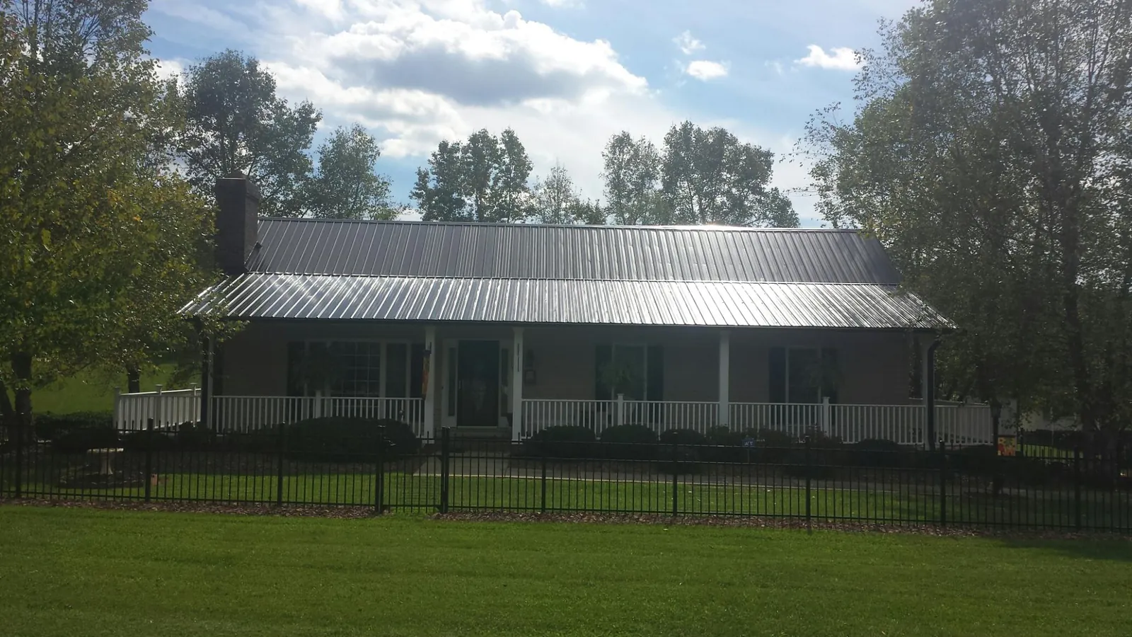 Gray metal roof on a brick ranch with a full width front porch — Gutter Guard Installation work by our crew in Arley