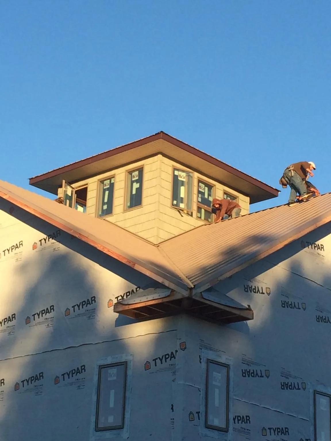 Roofers working around a rooftop cupola on a new metal roof at sunset — Roof Waterproofing in Arley by Roofing Brothers